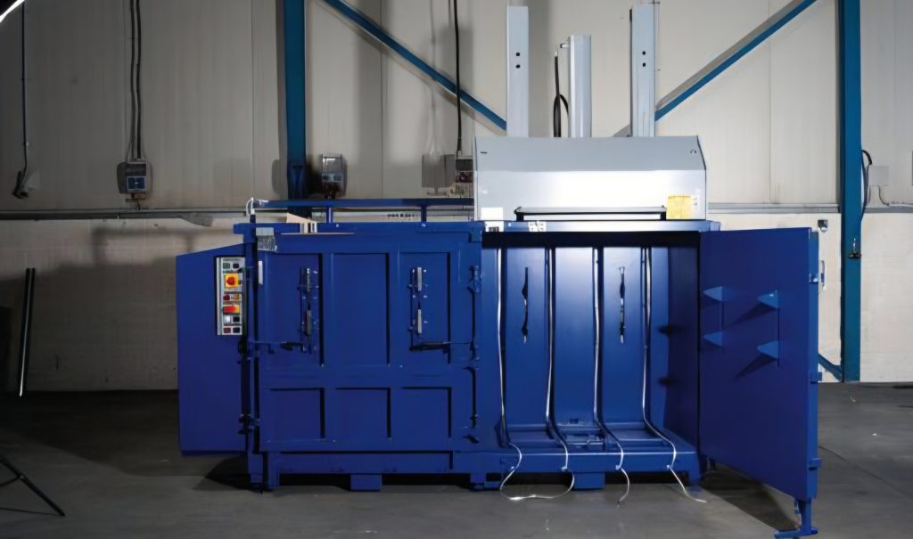 Müllpresse mit geöffneter Kammertür in einer Werkshalle